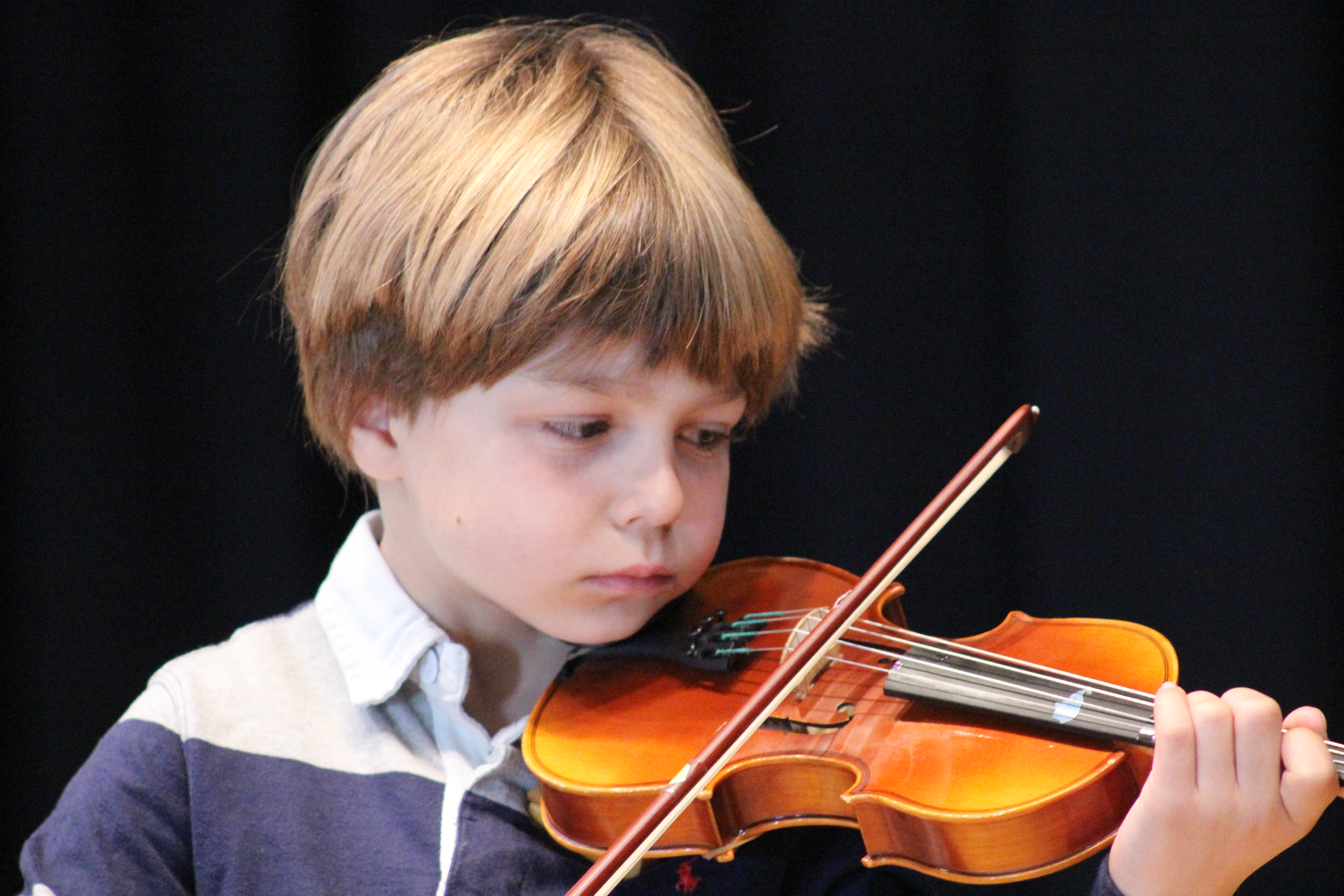 Violinista mirando su mano izquierda para comprobar la posición que ayuda a la afinación