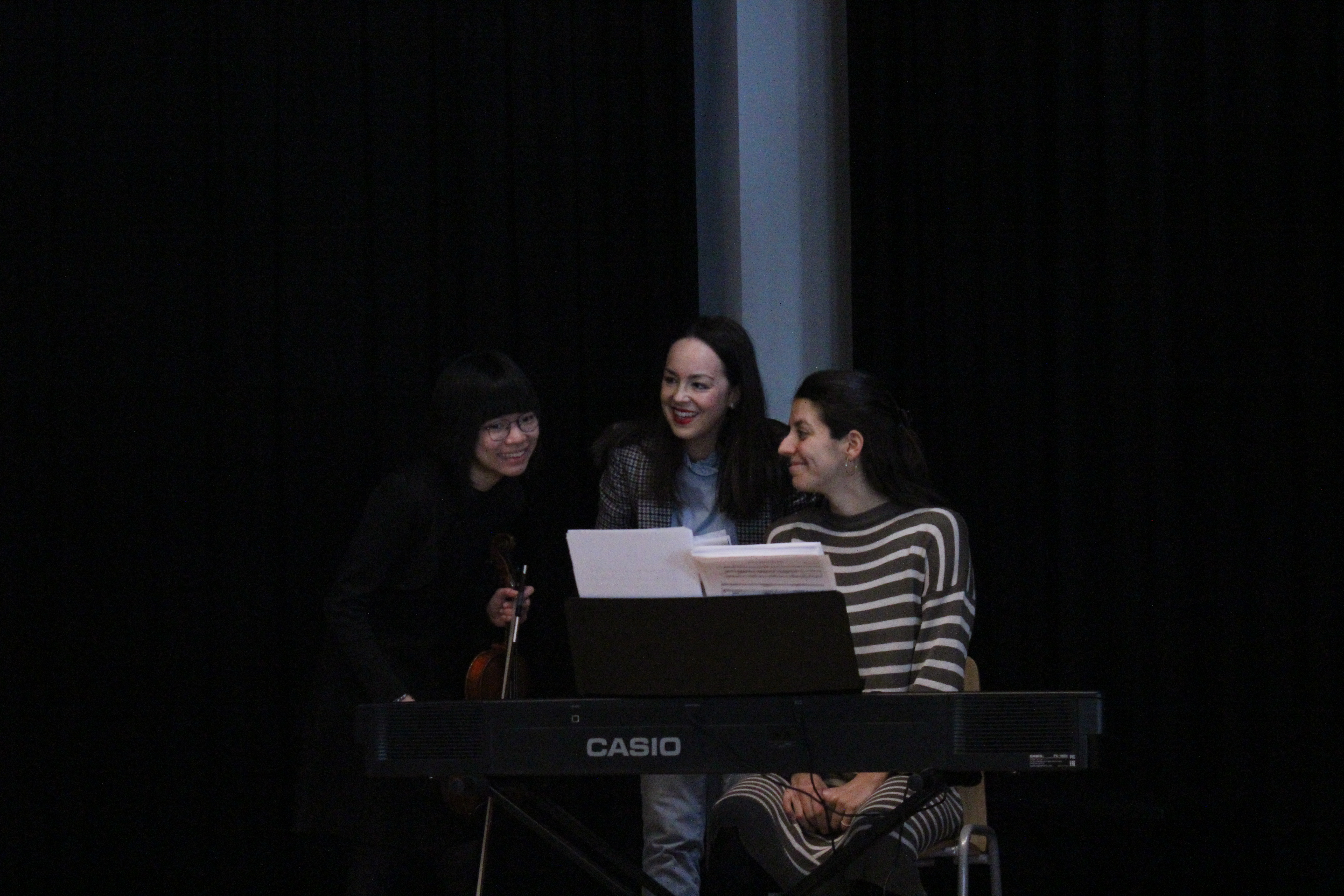 Profesora, pianista acompañante y alumna de violín riendo en el momento antes del ensayo general