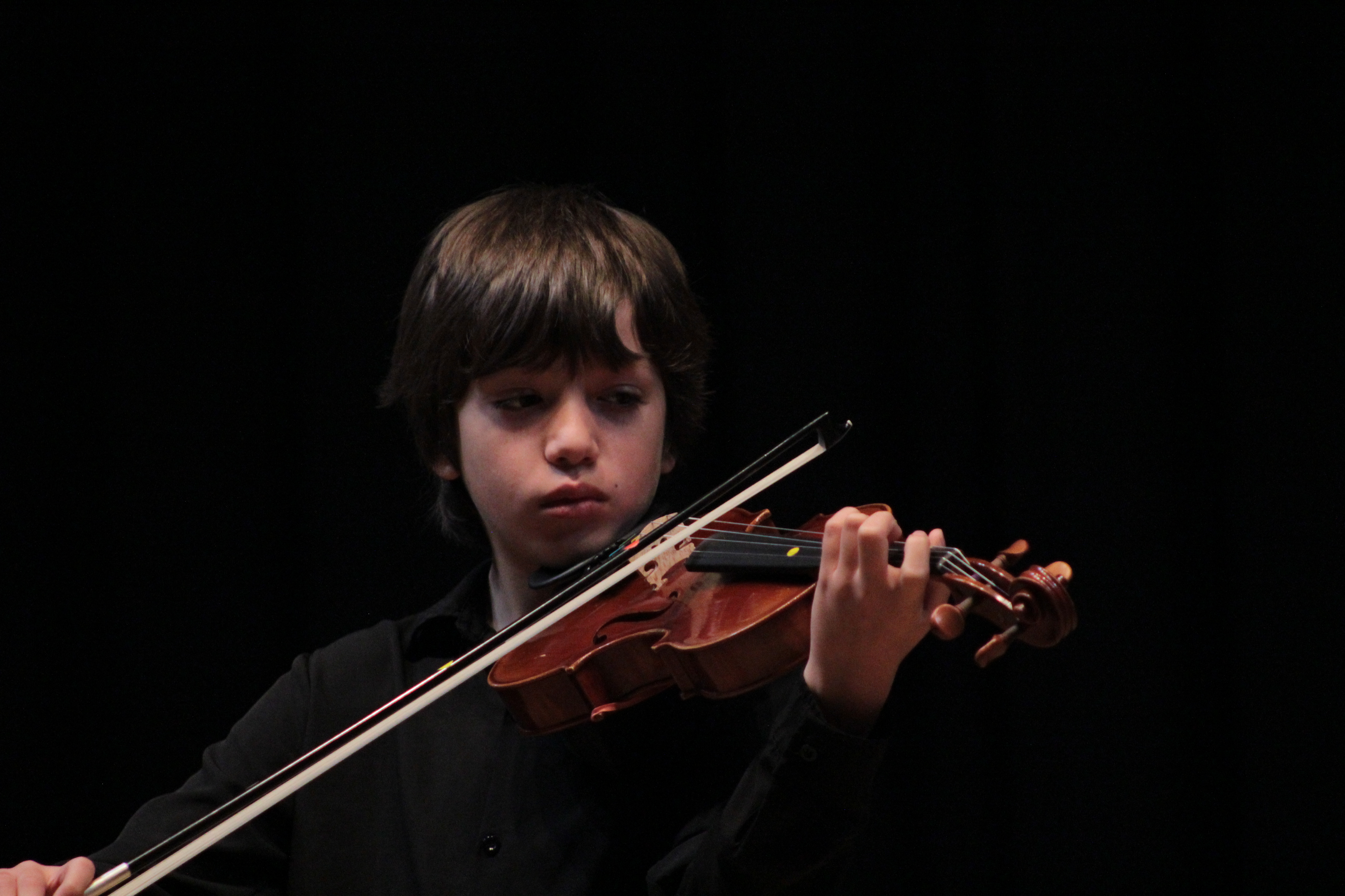 Alumno tocando el violín con la vista en ambas manos para controlar la coordinación