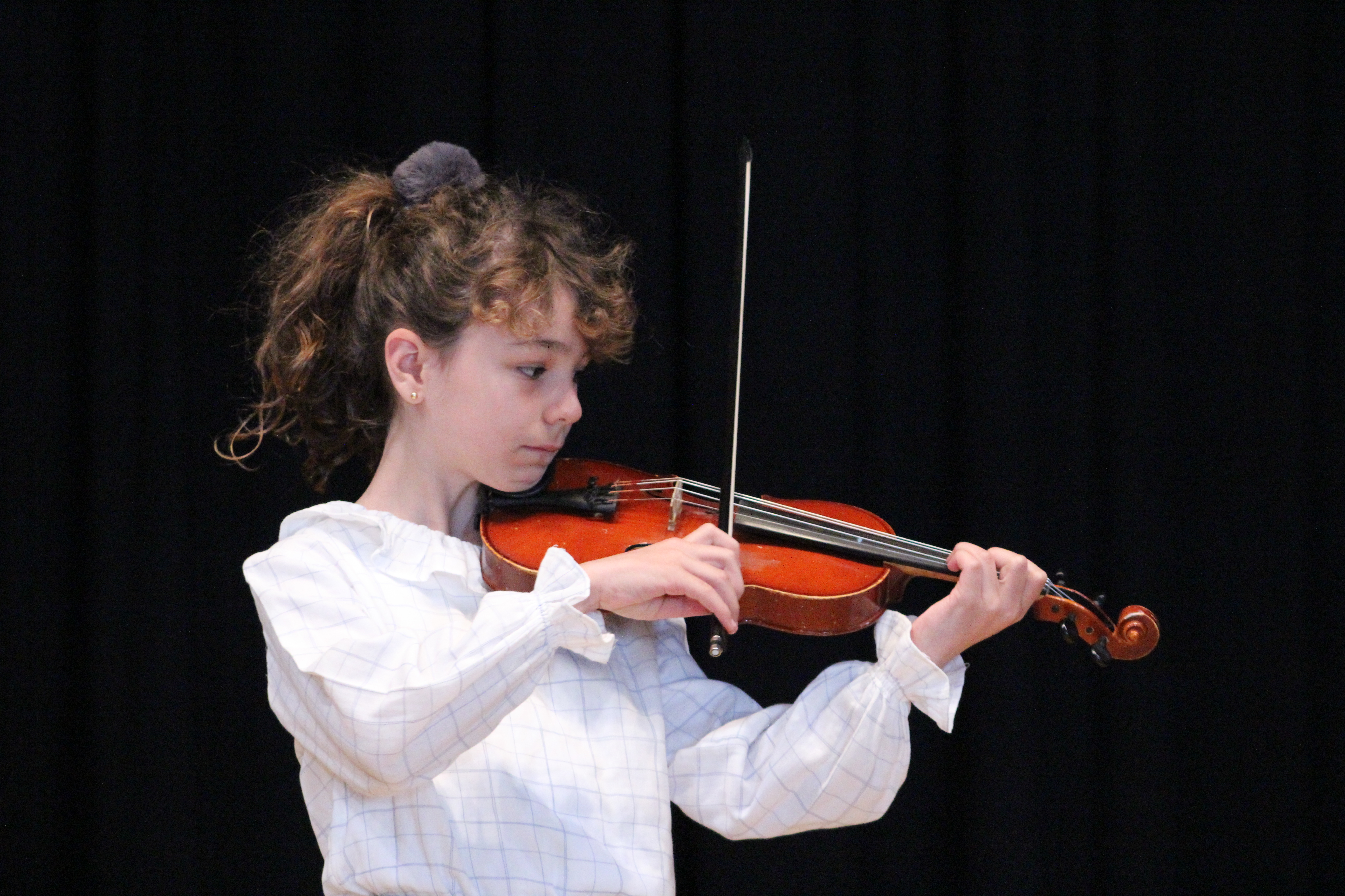 Niña tocando el violín con su arco totalmente perpendicular al puente, genial para el sonido